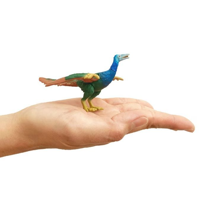  Toy dinosaur with blue neck, green body, and orange tail sits on a hand.