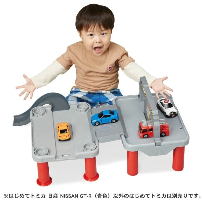  Toy car playset with a child. Includes a track, garage, and toy cars: police car, fire truck, and sports cars.