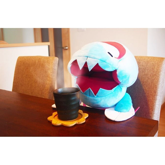  Blue Chomper plush toy with a cup on a wooden table.