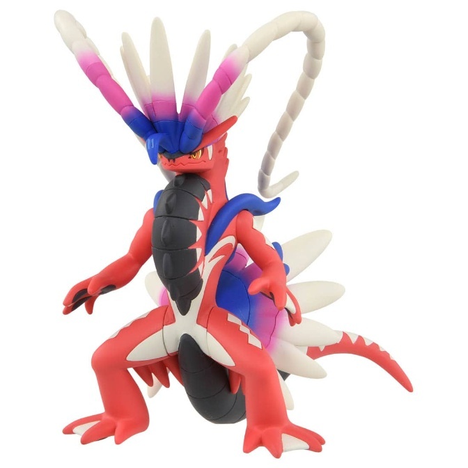Koraidon toy figure with red body, black armor, and colorful head spikes in a dynamic pose.