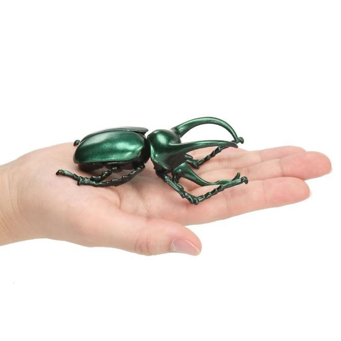  Green beetle toy with large pincers held in a hand.