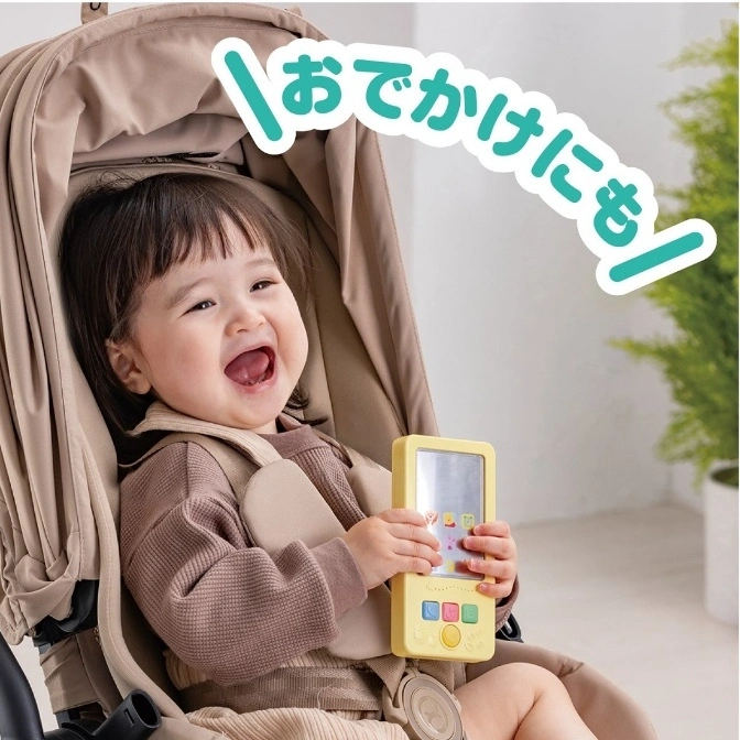  Baby in stroller holds a yellow toy phone with buttons and a reflective screen.