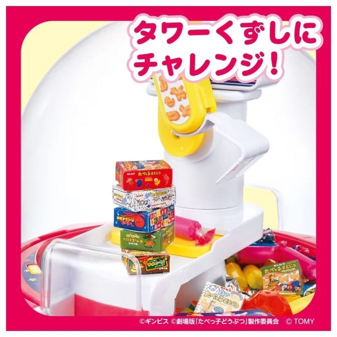  Tower stacking game with animal cracker boxes and a yellow claw. Candy pieces are scattered around the base.