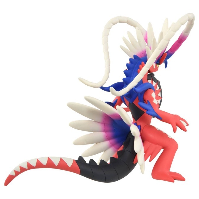 Koraidon toy figure, red and black with white accents, in a dynamic pose.