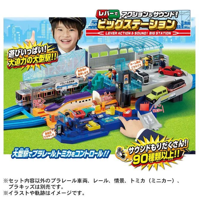  A toy train station set with a young boy in a conductor's hat in the background. The set includes trains, cars, and figures, and the packaging highlights the sound effects and lever-action features.