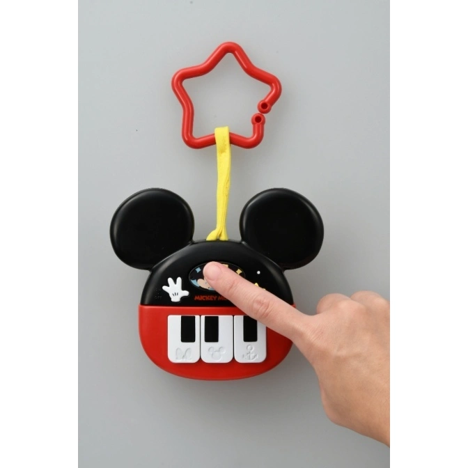  Mickey Mouse toy piano with star-shaped handle. A hand presses a button.
