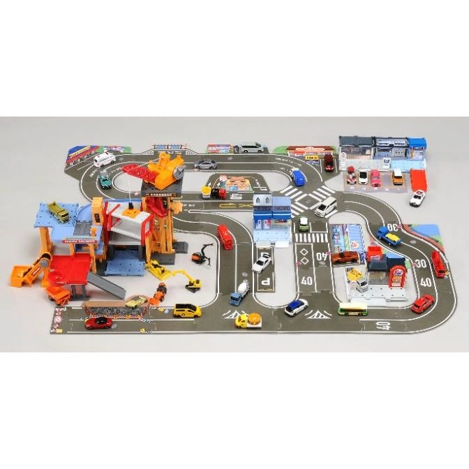  Tomica playset with roads, buildings, construction vehicles, and miniature cars arranged on a gray surface.