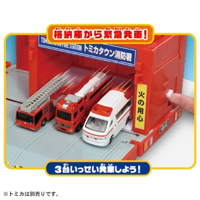  Tomica Town fire station toy set with three emergency vehicles and a button being pressed.