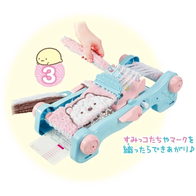  Light blue Sumikko Gurashi weaving toy with pink accents, yarn, and a hand weaving.