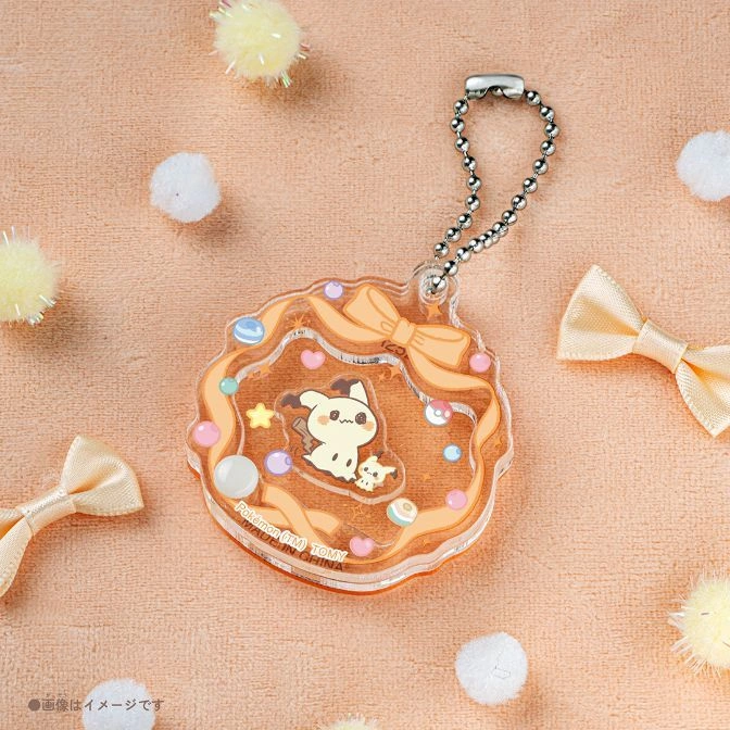  Mimikyu keychain with bows and beads on a silver chain, surrounded by pom poms and ribbons.