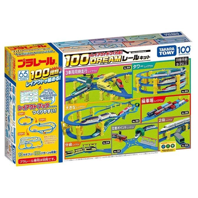 The product image shows a Takara Tomy Plarail 100 Dream Rail Kit box. The box is brightly colored and features various train layouts that can be built with the kit. The layouts include a tower layout, a large layout, a train yard layout, a two-level layout, a crossing point layout, and a branching layout. The box also indicates that the kit includes a layout book with 13 categories and 100 patterns. The age recommendation is 3 years and up.