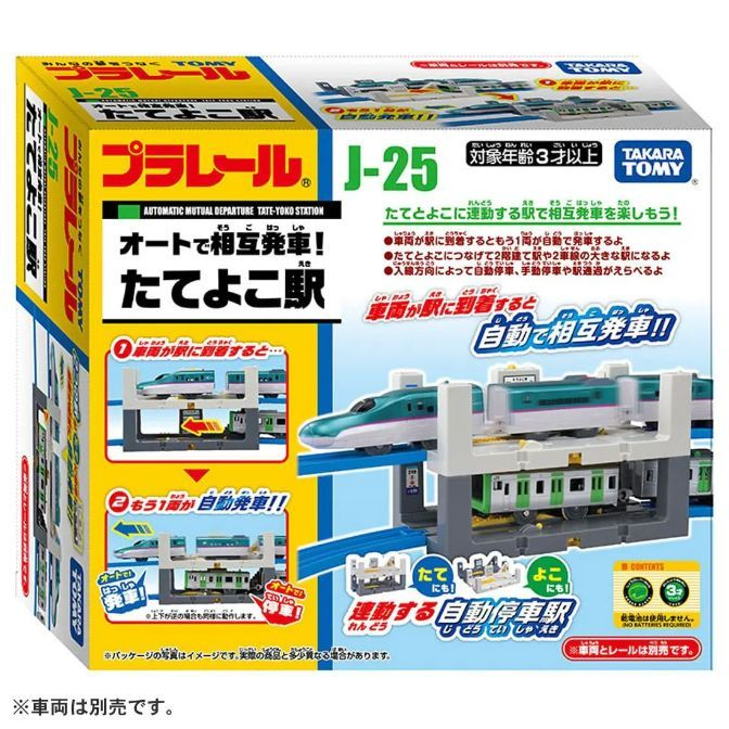  The product image shows a Takara Tomy Plarail J-25 Automatic Mutual Departure Tate-Yoko Station set. The box is yellow and blue, featuring images of the train station and trains. Text on the box includes the product name, age recommendation (3+), and descriptions of the station's features, such as automatic mutual departure and the ability to connect to other stations.