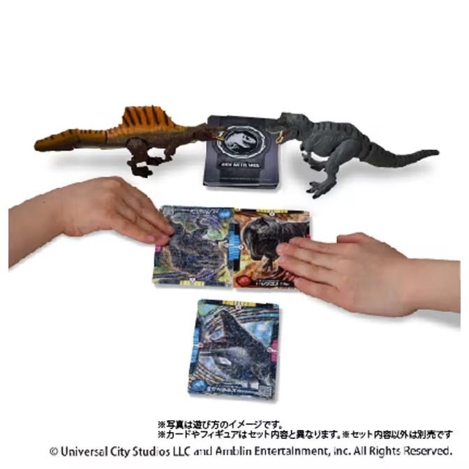  Dinosaur toys and cards being played with, featuring a Spinosaurus and Tyrannosaurus Rex.