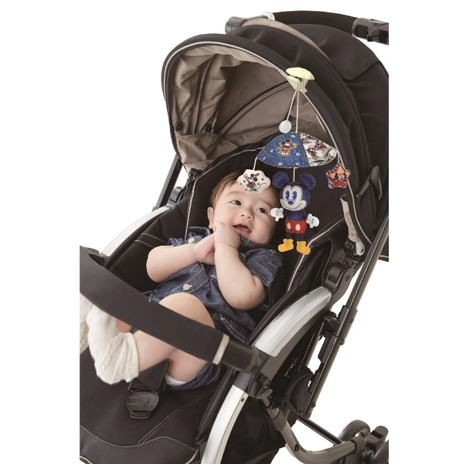  Baby in stroller with Mickey Mouse mobile toy hanging above.