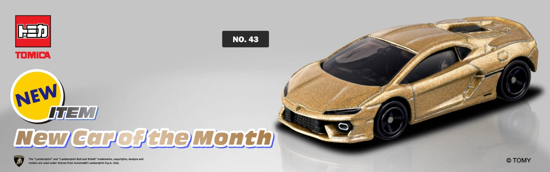 TOMICA New Car of the Month promotional banner featuring No. 43 Lamborghini Revuelto in metallic gold.