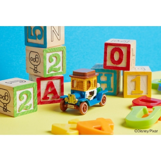  Toy Woody car surrounded by alphabet blocks and plastic letters on a yellow surface.