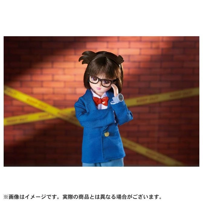  Conan Edogawa doll in blue suit, glasses, and bow tie, standing in front of a brick wall with caution tape.