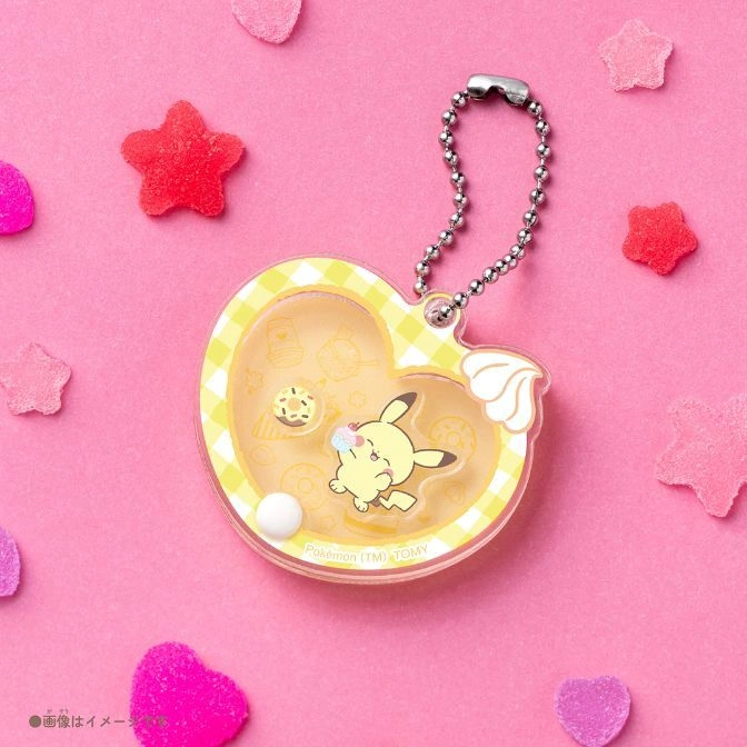  Heart-shaped Pokémon keychain with Mimikyu eating a donut, surrounded by candy on a pink background.