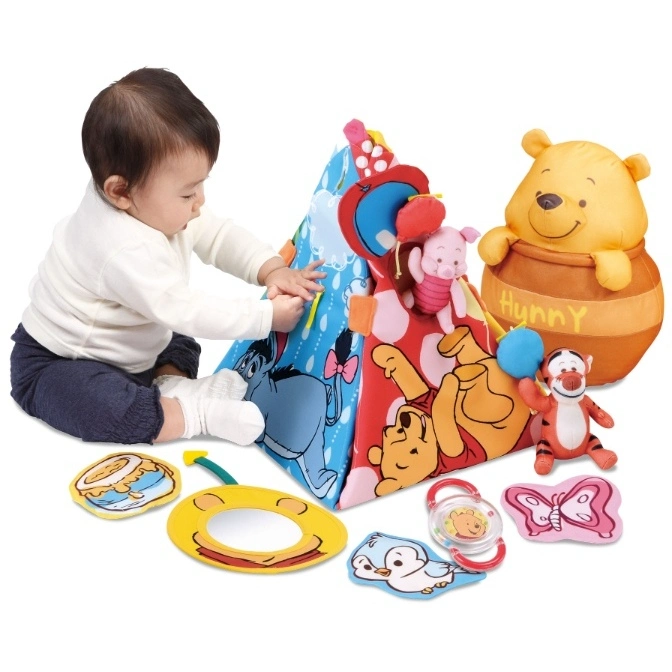  Baby playing with a Winnie the Pooh activity pyramid and plush toys.
