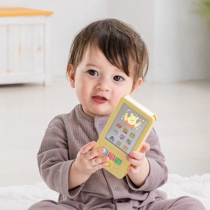  Baby holding a yellow toy smartphone with Winnie the Pooh on the screen.