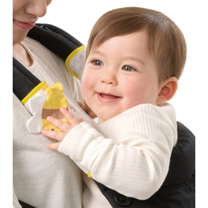  Baby in carrier with yellow toy. The baby is smiling and wearing a white shirt.