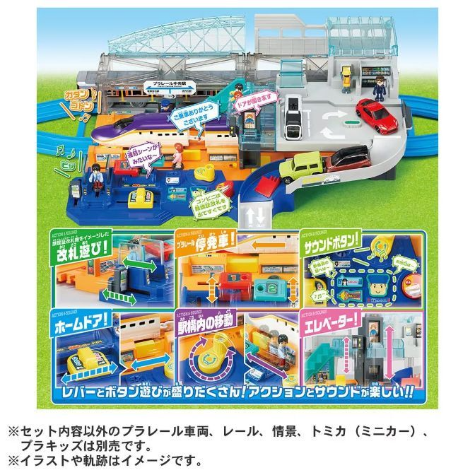  This is a product image of a toy train set. The set includes a train, tracks, a station, and several accessories. The station has a ticket gate, a convenience store, and an elevator. The train is purple and white, and the tracks are blue and green. The accessories include a car, a bus, and several figures.