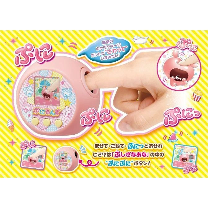 Pink interactive toy with screen, finger touching a hole. Japanese text and graphics surround the toy.