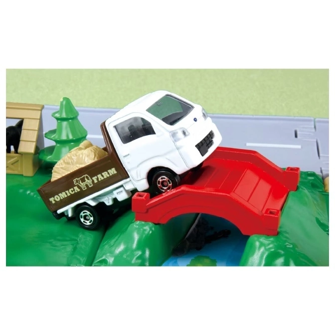  Tomica Farm truck on a red bridge, carrying hay. A toy farm set with a dog house and tree are nearby.