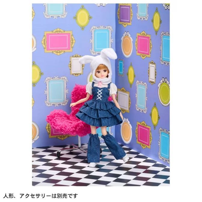  Doll in bunny hat and denim dress, posed in a whimsical room with checkered floor and framed pictures.