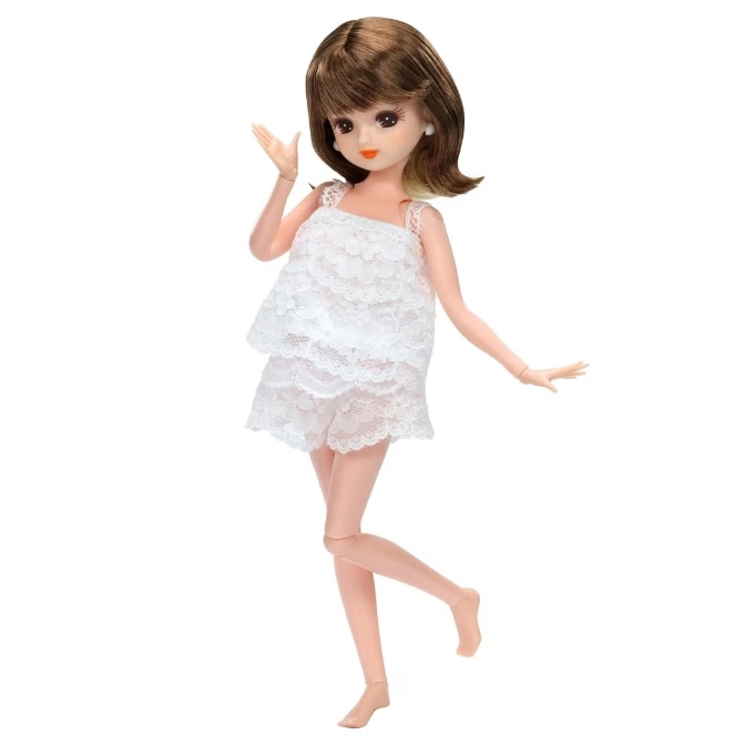 Doll with brown hair wearing a white lace top and shorts, standing on one leg.