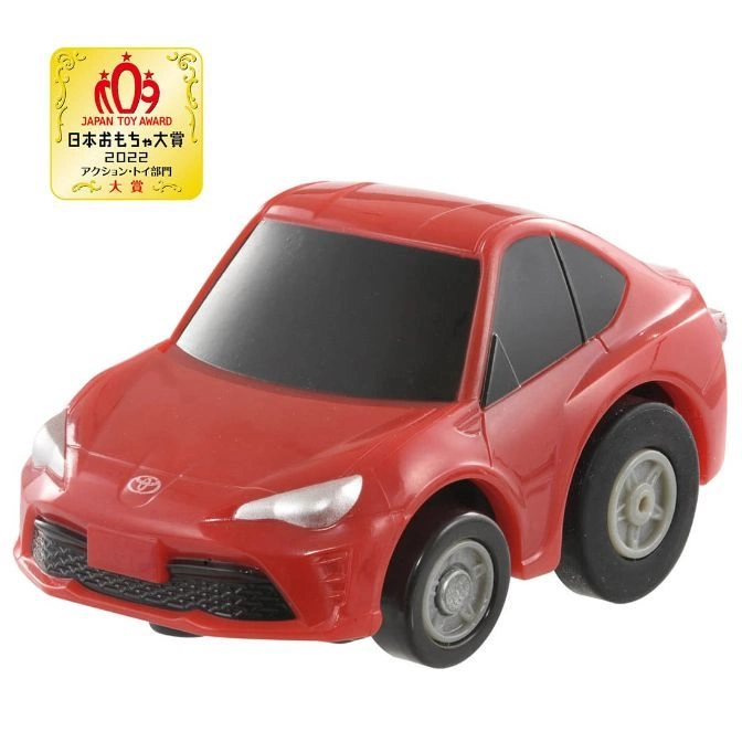 Red toy car with Japan Toy Award badge. A small, cartoonish version of a sports car.