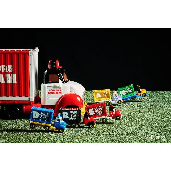  Disney toy truck set with lettered trailers spelling "DREAM", on a green surface.