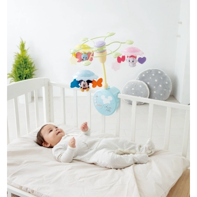  Baby in crib with Disney mobile featuring Mickey Mouse and friends.