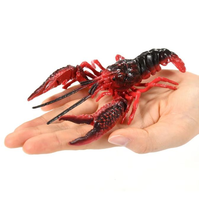  Red and black toy crawfish on a hand, showcasing its claws and detailed texture.