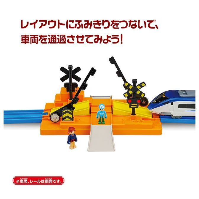  A toy train set with a crossing gate and two figures.