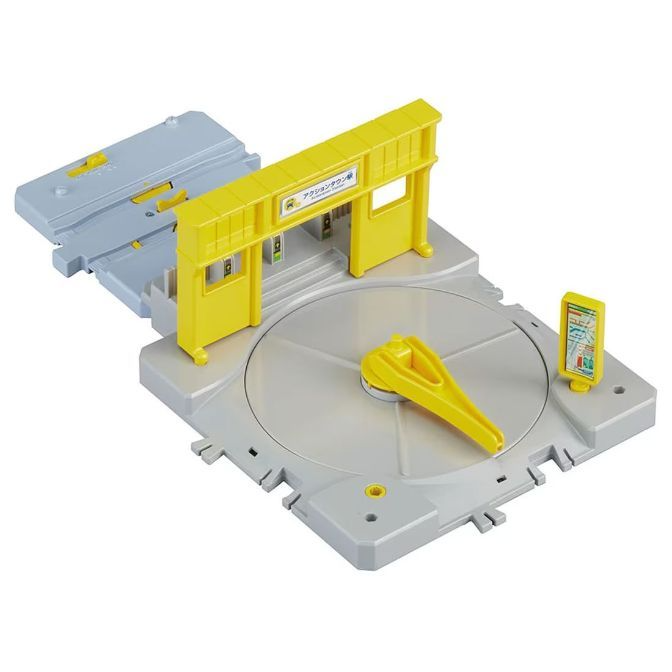 A toy train station with a turntable and a yellow gate.