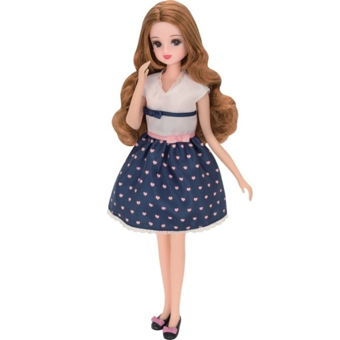Doll with long brown hair, wearing a white and navy heart-print dress with black shoes.