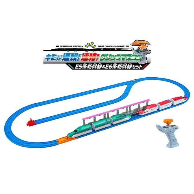  A toy train set with a blue track, a green and white train, a red and white train, a bridge, and a controller.