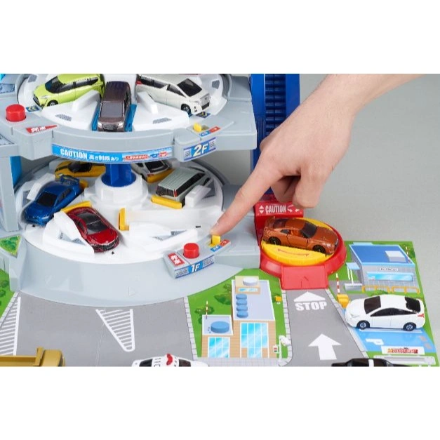 Toy car park with cars, hand pressing button. Multi-level garage with ramp, turntable, and road markings.