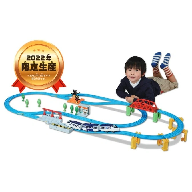  Toy train set with a boy lying next to it. The train is blue and white, and the track is blue.