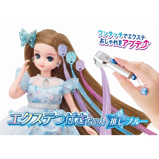 Doll with hair extensions being applied using a styling tool. Features blue accents and flower hair clips.