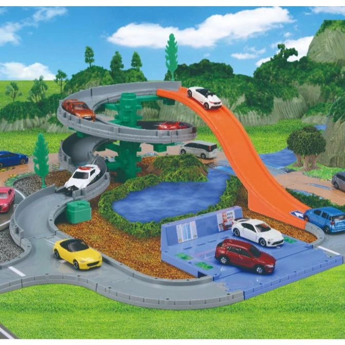  Toy car playset with winding tracks, ramp, lake, and various miniature vehicles in a scenic landscape.