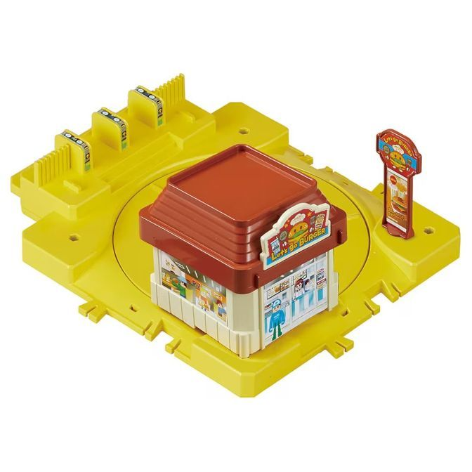 A toy set featuring a yellow base with a circular track, a burger restaurant with a brown roof, and a menu board.