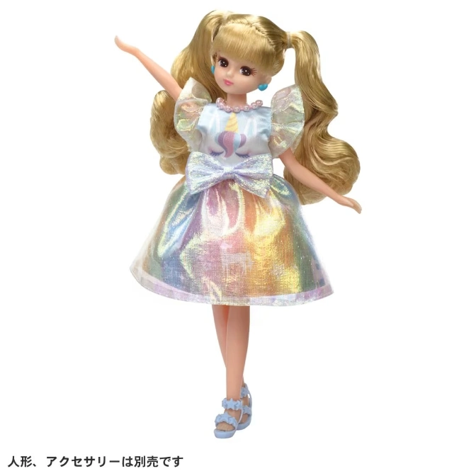  Blonde doll in rainbow unicorn dress and blue sandals, arm raised.