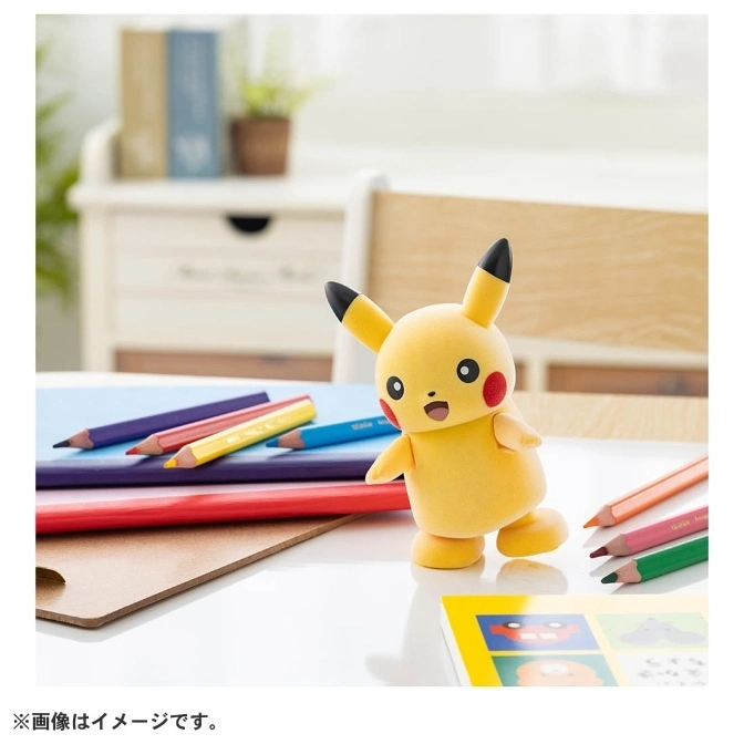  Pikachu toy figure standing on a desk with colored pencils and books.