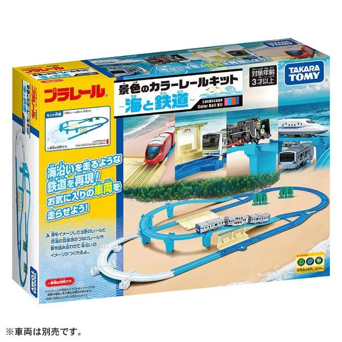  The product image shows a Takara Tomy Plarail Landscape Color Rail Kit, featuring a blue and white train track set designed to resemble a coastal railway. The box displays various trains, including a red bullet train, a black steam engine, and a modern commuter train, along with a station and elevated sections of track. The set is recommended for ages 3 and up, and the packaging emphasizes the theme of trains running along the sea.