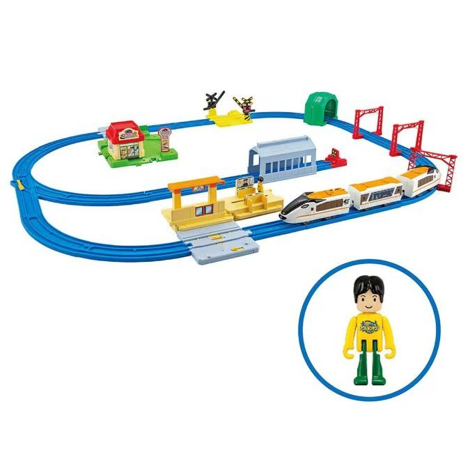 Toy train set with train, tracks, buildings, and a figure.