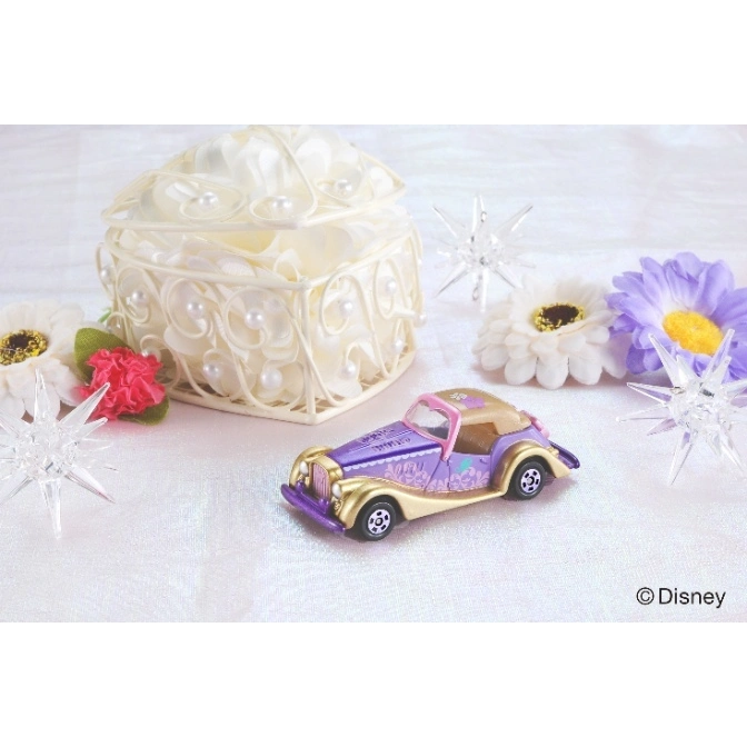  Purple and gold toy car with floral details, surrounded by flowers and a heart-shaped box.